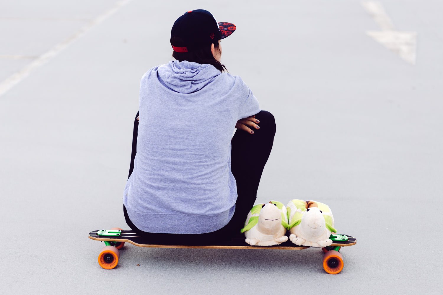 Person sitzt auf Skateboars und daneben steht ein Paar lustige Schildkrötenhausschuhe