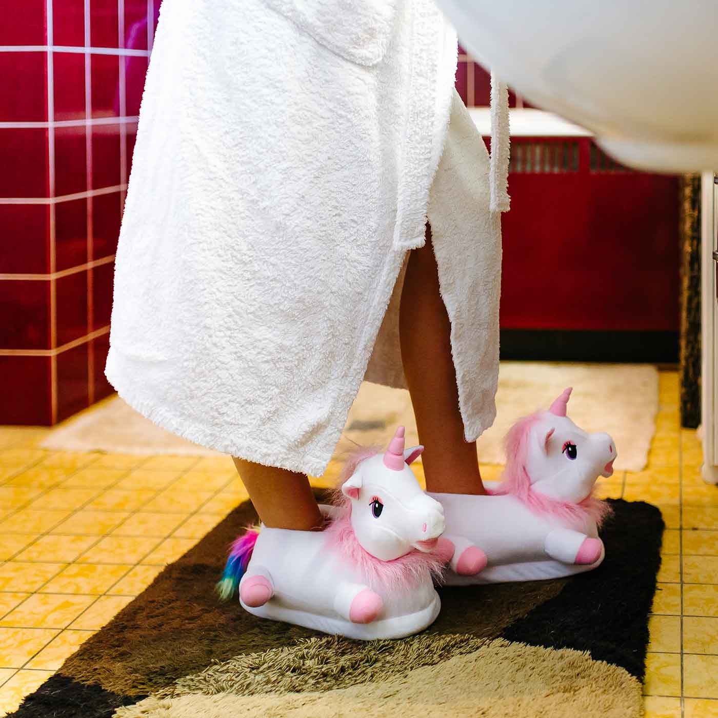 Person im Bad trägt süße Einhornhausschuhe in weiss-pink