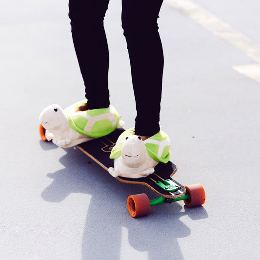 Person mit Schildkröten Hausschuhe auf Skateboard